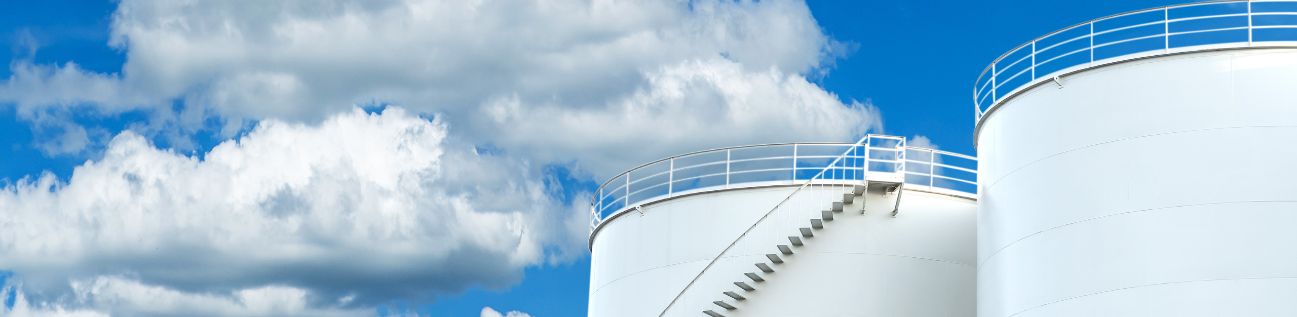 Two LNG storage tanks against a blue sky.