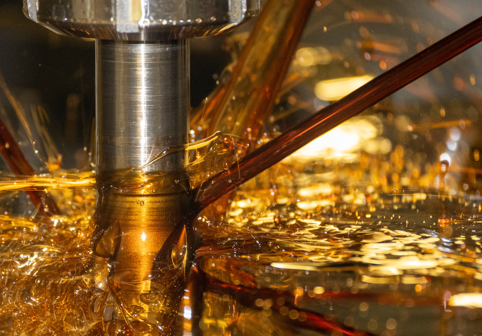 Close up of industrial lubricant being poured onto machinery.