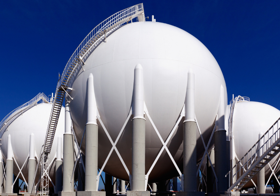 Three LNG liquified natural gas storage tanks against a deep blue sky.
