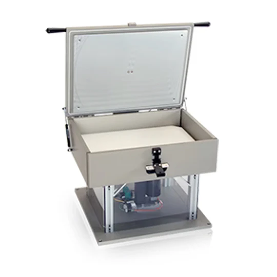 Open metal testing chamber with a transparent lid, placed on a platform.