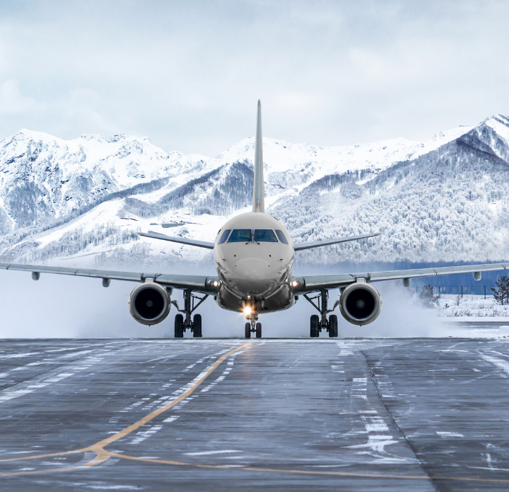 Airplane front view landing on a snowy runway with majestic snow-covered mountains in the background, conveying a sense of adventure and precision.
