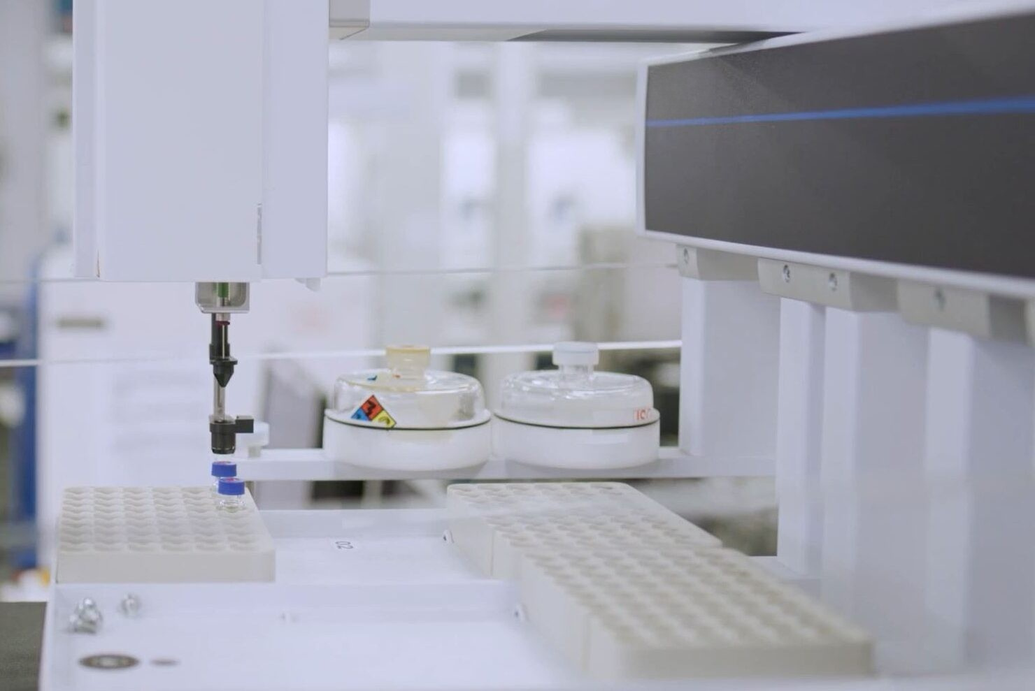 Close-up of laboratory equipment in a sleek, sterile lab setting. Robotic arm holding a vial over a rack; analytical instruments and samples nearby. Image taken from Marathon ElemeNtS testimonial and intended for use on elemental analysis page.