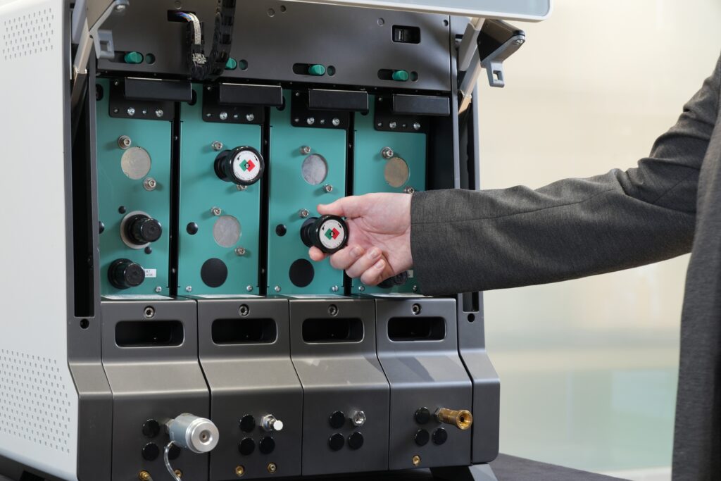 A man reaching out to tug on a module of a large laboratory device's front panel.