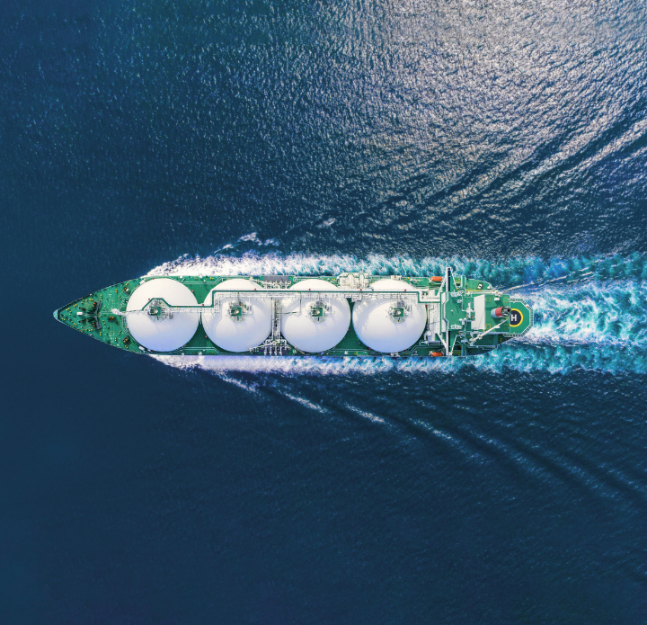 Aerial view of a large LNG tanker navigating through the open ocean, surrounded by deep blue water. LNG Analysis.